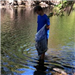 Young man standing in water looking for garbage